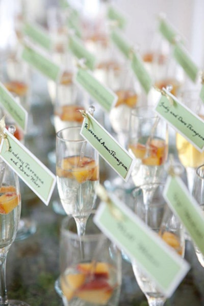 Escort cards on custom drink stirrers were placed in glasses of white peach sangria at a summer wedding produced by Camp Hill, Pennsylvania-based catering and events company the JDK Group.
