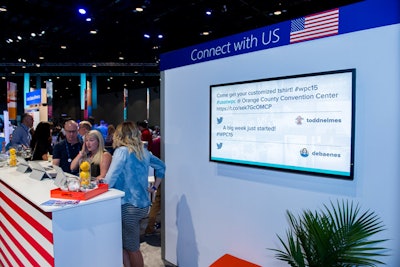 Behind the lounge's welcome counter, a monitor displays social media posts using #usatwpc, a hashtag specifically for the U.S. partner experience.