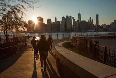 A sunset shines on the New York City skyline and hunters in Brooklyn Heights.