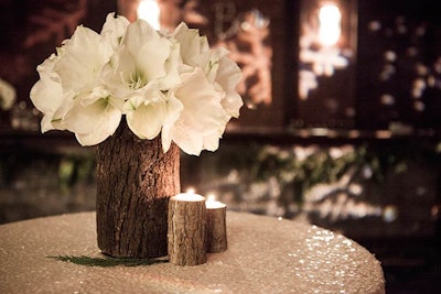 Tree stumps served as vases for white amaryllis flowers as well as candleholders and added a contrasting element to the glittery sequin linens at the corporate gathering.