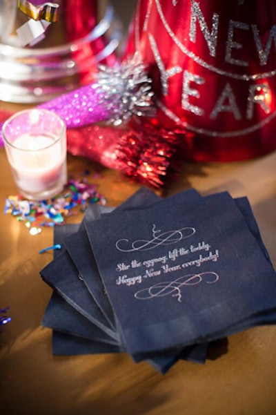 Black cocktail napkins feature a clever New Year toast in silver ink.