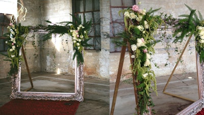 Oversized mirror frame hung with greenery for a rustic-chic wedding ceremony