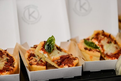 Deep-dish pizzas with a house-made olive oil crust, tomato ragout, mozzarella, and basil, served with tiny shakers of Parmesan, garlic powder, oregano, and red pepper flakes, by Abigail Kirsch in New York