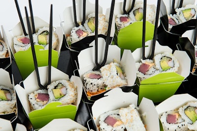 Sesame noodle salad with Asian vegetables, garnished with spicy tuna and California rolls, served in individual take-out containers, by Abigail Kirsch in New York