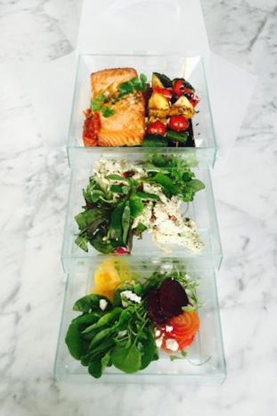 A bento box filled with heirloom beet and watercress salad with goat cheese and spiced pistachios; open-faced roasted chicken salad on a pretzel croissant; and olive-oil-poached salmon with tomato-fennel chutney and balsamic roasted vegetable skewers, by Truffleberry Market in Chicago