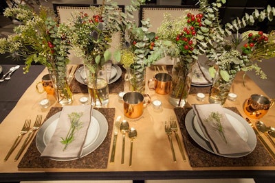 A similarly natural, garden-like design appeared at a table decorated by OFS Brands and student members of the American Society of Interior Design Illinois. With no linens, the table had leafy floral arrangements dotted with berries, and napkins were topped with delicate green sprigs. Settings included copper mugs, golden flatware, and wooden place mats.