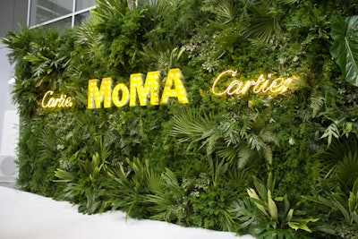 The arrivals backdrop—featuring the Cartier, which underwrote the event, and MoMA logos rendered in neon and marquee lights—echoed the dense arrangements of tropical greenery found inside the dinner space.