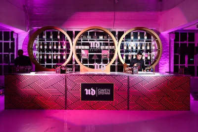 The bar design was inspired by the collection, using its graphic print on the front with gold circles behind the bar that recalled the eye shadow and blush palettes. Gold glitter champagne bottles customized for the event rounded out the display.