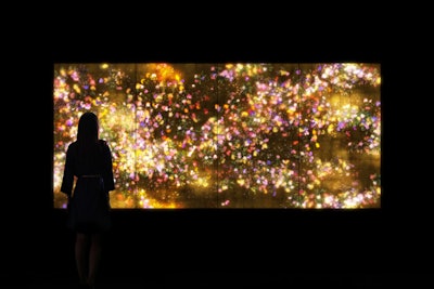 Teamlab has expanded the practice of digital-art creation. Its current large-scale installation in Silicon Valley measures 20,000 square feet, spans multiple rooms, and includes 20 digital works. One of the works (pictured) is called 'Flowers and People—Gold.' The artwork is displayed in real time by a computer program and showcases the cycle of flowers budding, growing, blossoming, and withering. The interaction between the viewer and the art creates constant changes in the piece, and its previous visual states cannot reoccur.