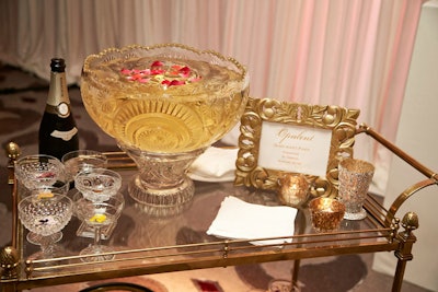 An elderflower champagne cocktail with an edible flower garnish in crystal coupe glasses, accompanied by a large crystal punch bowl on a vintage gold bar cart, was presented at the Toast the Trends event hosted by the Four Seasons Hotel Chicago and bridal company Elaya Vaughn by Kate Pankoke in September.
