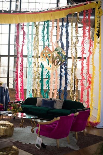 The company handmade more than 100 feet of tissue paper fringe in nine different colors to hang across the ceiling and use as a backdrop behind the lounge seating at a winter event.