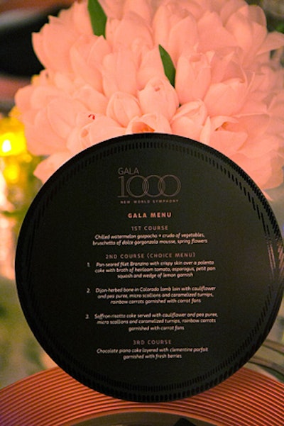 The menu was printed on circular cards. Prepared by Thierry's Catering, courses included chilled watermelon gazpacho, bone-in Colorado lamb, and saffron-risotto cake. Dessert was a 'chocolate piano cake' layered with clementine parfait.