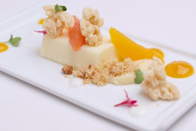 Blood orange segments served with creamy mascarpone cheesecake, white chocolate crisp, red liquid gel, Florida citrus ganache, and edible micro flowers, by Puff ‘n Stuff Catering in Orlando