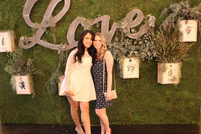 Guests posed in front of a mossy step-and-repeat-style backdrop, where branches and plants created three-dimensional visual interest.