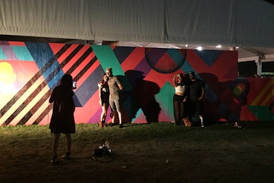 A street art-like mural decorated the side of the massive merchandise tent, beckoning festival-goers to pose for photos against the colorful backdrop.