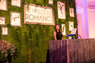 Backing the rustic wood-fronted DJ booth was a wall of greenery, decorated with framed botanical art.