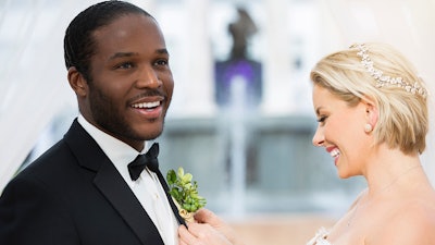 A bride and groom stand in front of the Broadway Fountain.