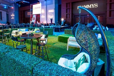 Design Foundry created an indoor garden with two-foot hedges and faux grass turf in front of the dance floor. Hanging wicker chairs and a mix of hightop wooden stools and white canvas lounge furniture provided seating.