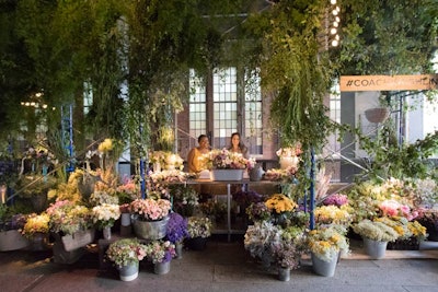 A dedicated area underneath the passageway housed a flower crown tableau. Hundreds of crowns were pre-made for guests, each affixed with a thin strip of leather in a nod to Coach's roots. Among the florals brought in: spray roses, wax flower, chamilia, button mums, lisianthus, scabiosa, jasmine, and clematis. Toward the end of the evening, guests were able to create bouquets to take home.