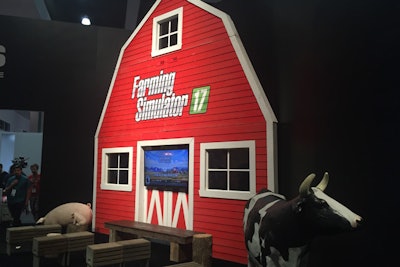 In keeping with the Farming Simulator franchise's traditional farm-inspired setup, this year's exhibit featured a red barn complete with rustic seating in front—and life-size statues of a cow and pig.