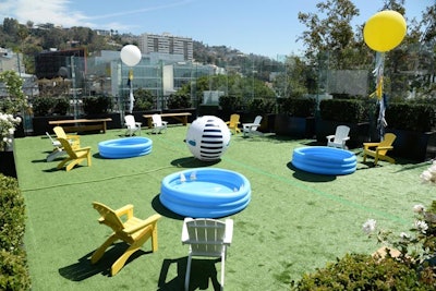 On the sweltering event day, guests made use of a turf-covered, lawn-like area for water activities. Large spherical balloons surrounded the area, where parents could watch kids play from yellow and white Adirondack chairs.