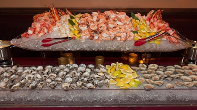 Raw bar display: raw oysters and littleneck clams, chilled shrimp, lobster, and crab legs