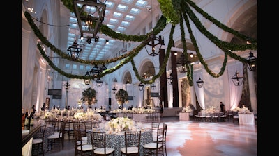 Suspended greenery hanging over classic white centerpieces at dining tables.