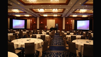 A dual screen with a podium and stage in the hotel ballroom