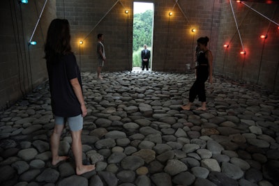Two installations, both by G.T. Pellizzi, were combined inside the primary entranceway of the Watermill Center's main building. 'Constellations in Red, Yellow and Blue' was featured on the walls, complementing the Bruce High Quality Foundation's 'As We Lay Dying: Singing Quartet' of performers. The former featured light sculptures derived from invented cosmologies inspired by symbols found on many textiles in the Watermill Collection, while the latter featured singers rhythmically singing and breaking up the texts that have been ringing throughout the grounds.