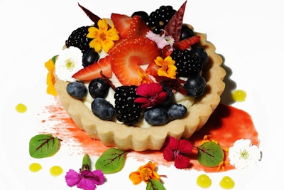 Edible flowers are another decorative garnish that can be used with meats or served with desserts, like this key lime fruit tart topped with strawberry hibiscus fruit leather, and garnished with strawberry sauce painting, lemon sauce, and micro edible flowers.