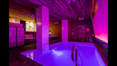 An indoor pool with a DJ booth and two big walls to project