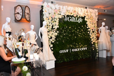 The #GiltLife House's bridal event took place October 4. The event's step-and-repeat was decorated to match the theme and showcased Oscar de la Renta wedding dresses. Programming partner Perrier Jouet offered guests glasses of champagne, and bottle displays were weaved into the decor.
