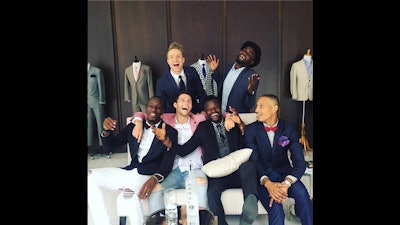 Azeez and male models pose in front of suits.