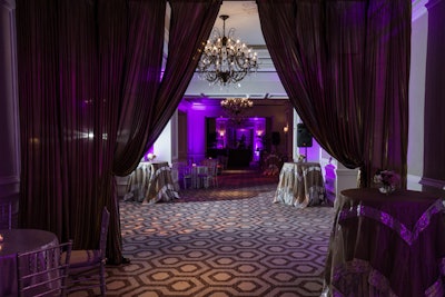 Grey and silver drape created an entryway to the reception space as guests arrived on the lower level of the Ritz-Carlton. VSG Solutions used purple and gold lighting in the area to complement the gold and metallic linens on the cocktail tables and drape.