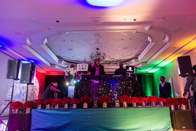 DJ Sixth Sense performed from an elevated DJ booth adorned with black palette linens, a nod to the event's 'Shine' theme. Arrangements of red roses lined the stage in front of him.
