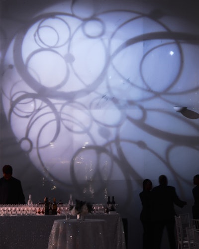 Circular projections on the walls of the dinner space added dimension to the blank walls and complemented the white and silver of the tables and place settings.