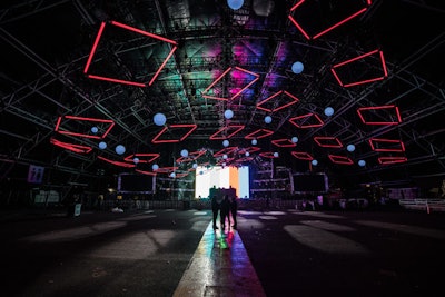 Guests assembled under a pattern of glowing squares as part of a ceiling installation.