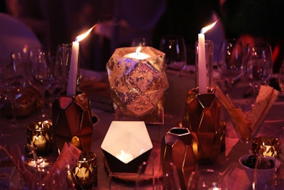 Angular candleholders and vases in gold and bronze tones decorated white lacquered dining tables.