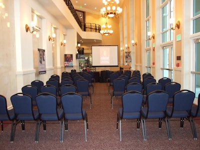 Miramar Cultural Center's theatre lobby set for corporate presentation with projector screen, microphone and podium.
