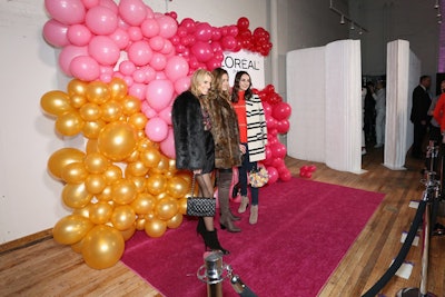 The step-and-repeat featured a cascading balloon sculpture in the event's color palette of reds, pinks, and yellows.