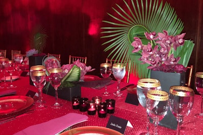 Volanni created four floral designs incorporating red toned flowers, monstera leaves, succulents, lily grass, and accents of mini cymbidiums blossoms for the dinner table centerpieces.