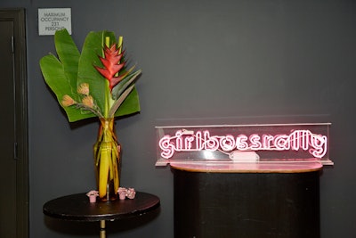 A neon sign spelled out the inaugural event's name, alongside an arrangement of tropical flowers and foliage.