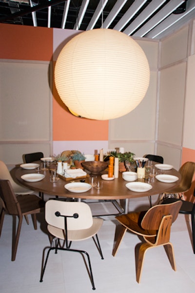 Herman Miller's vignette featured a mix of chairs from the company’s iconic designs. A large glowing spherical lantern hung above the table.
