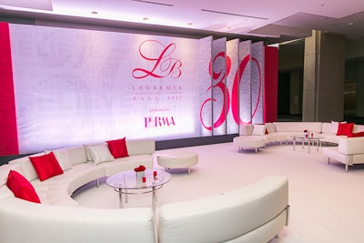 An all-white lounge featured accents of red in the flowers, pillows, and signage. The space provided a respite for guests waiting for the valet at the end of the evening.