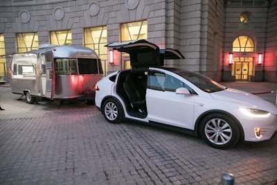 A Tesla parked in the plaza of the Ronald Reagan Building had an Airstream trailer attached to showcase its towing capability. Event guests could then go inside the trailer to customize their own Tesla in a computer design program.