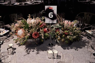 Floral centerpieces studded with proteas in muted hues were displayed using industrial materials.