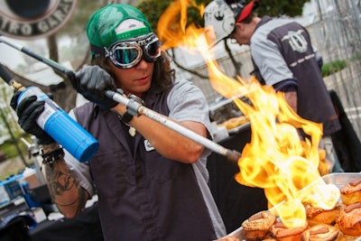 Food vendor the Gastro Garage created artisanal sweet and savory doughnuts, finished on-site with power tools and flame torches by staff costumed to resemble a pit crew. Tool boxes, welding helmets, and oil tin cans decorated the food station.