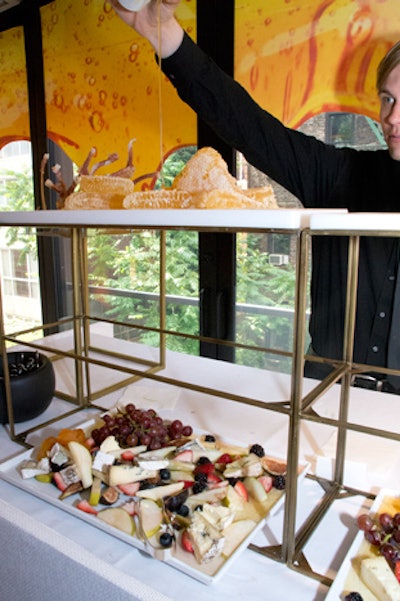A raw honeycomb serving station played off Miel-en-Mousse, a new cleanser with acacia honey; a server poured honey from above, which dripped onto cheese and fruit platters.