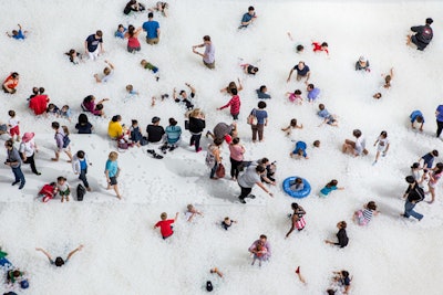 Interactive installation “The Beach” features a sloped floor that leads to an “ocean” of one million recyclable, antimicrobial plastic balls.