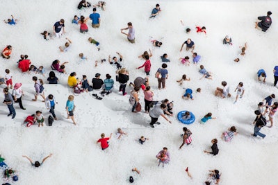 Interactive installation “The Beach” features a sloped floor that leads to an “ocean” of one million recyclable, antimicrobial plastic balls.